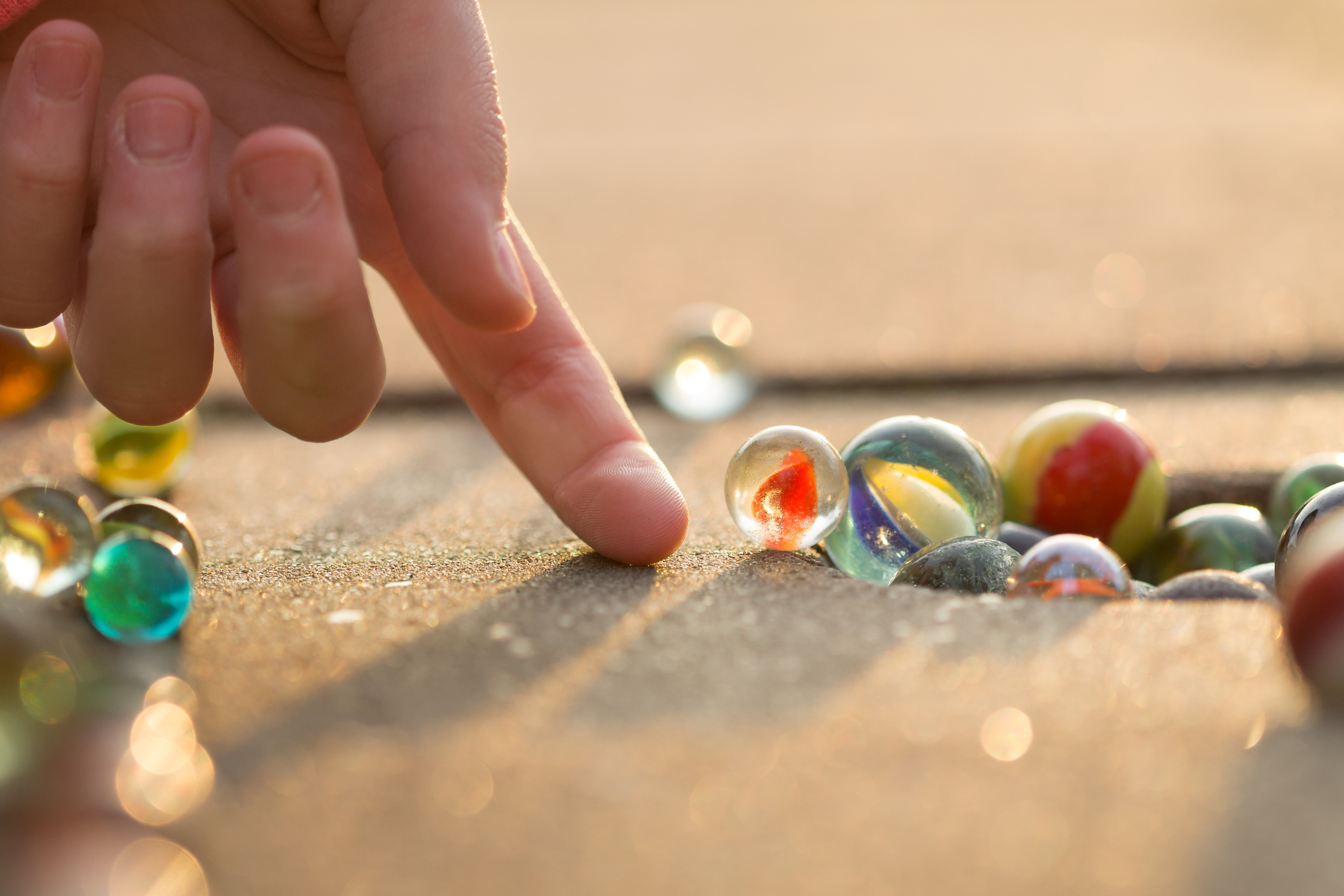 Child playing with marbles on yhe sidewalk. kuličky